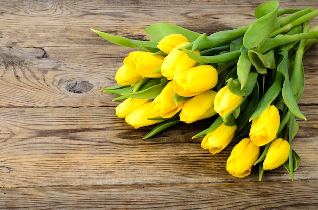 Yellow tulips lie on an old wooden surface