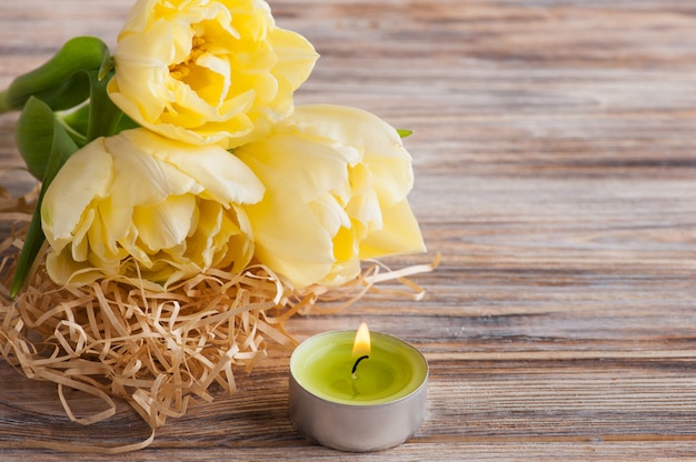 Yellow tulips, lit candle