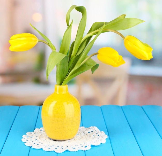 Tulipani gialli in vaso sul tavolo di legno sullo sfondo della stanza