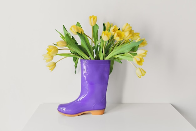 Yellow tulips in the violet rubber boots