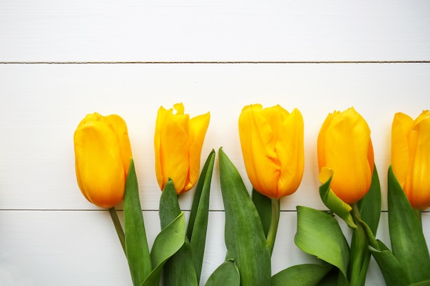 Yellow tulips on white wooden table. Top view with copy space