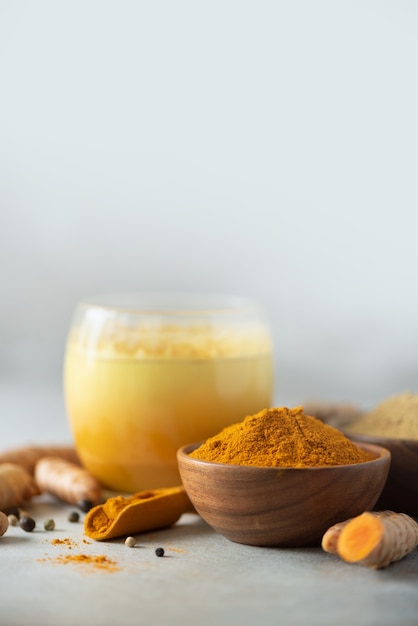 Bevanda gialla del latte di curcuma. latte dorato con cannella, curcuma, zenzero su sfondo grigio. copia spazio