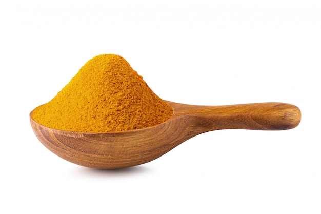 Yellow turmeric powder in a wooden spoon isolated on white