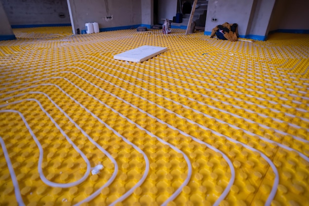 Photo yellow underfloor heating installation with white polyethylene pipes on construction site of new two level apartment