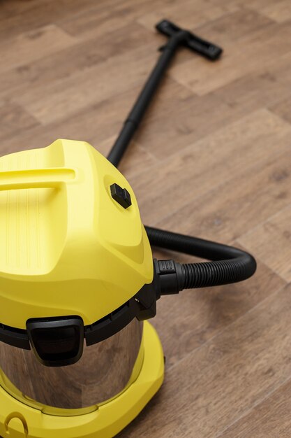 Yellow vacuum cleaner isolated on floor of the parquet in a room