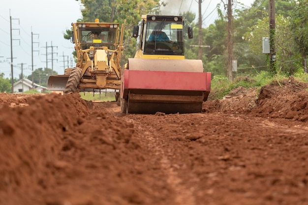 Yellow vibratory soil compactor working on highway construction site.