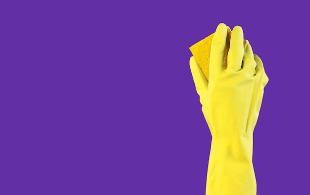 Фото Желтая моющая губка в руке в перчатке на фиолетово-фиолетовом фоне рекламный баннер для профессиональной уборки