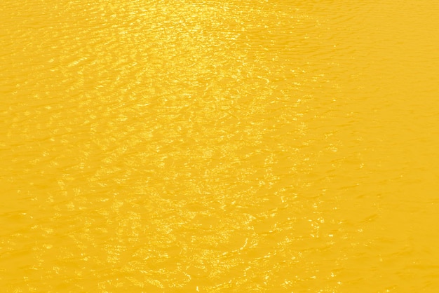 Желтая вода с рябью на поверхности Расфокусируйте размытую прозрачную прозрачную спокойную воду золотого цвета