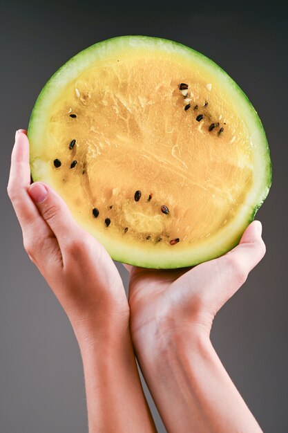 Yellow watermelon in hands.