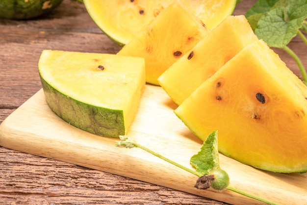 Yellow watermelon with fresh leaves on the wooden background