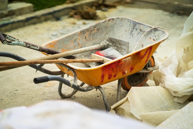 Photo yellow wheel barrow with various items at the construction site