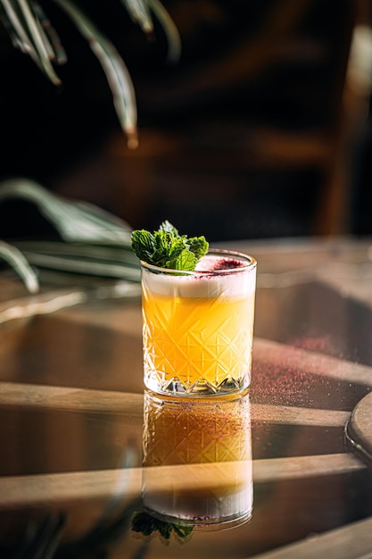 Yellow whisky sour cocktail garnished with mint