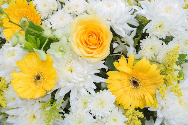 黄色と白の菊の花のバラは、葬儀で花輪を使用するために緑の葉で飾られました
