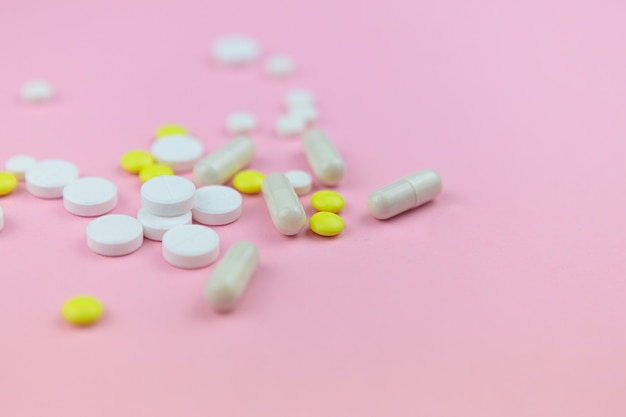 Photo yellow and white pills and capsules in pink table