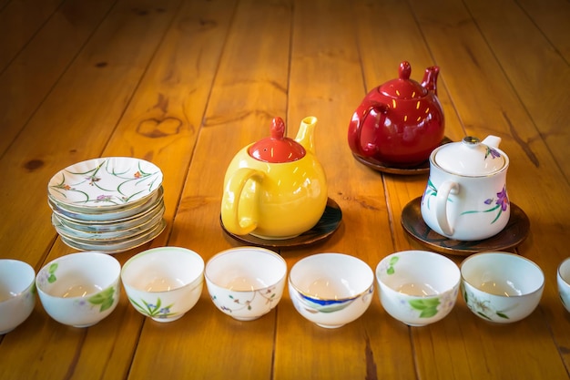 Yellow White and Red tea pot on the wood table with white dish and cup in the front row of them