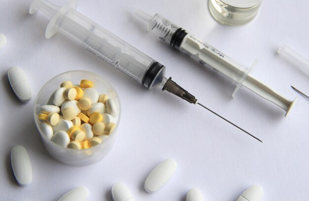 yellow and white tablets with disposable syringes on a light background