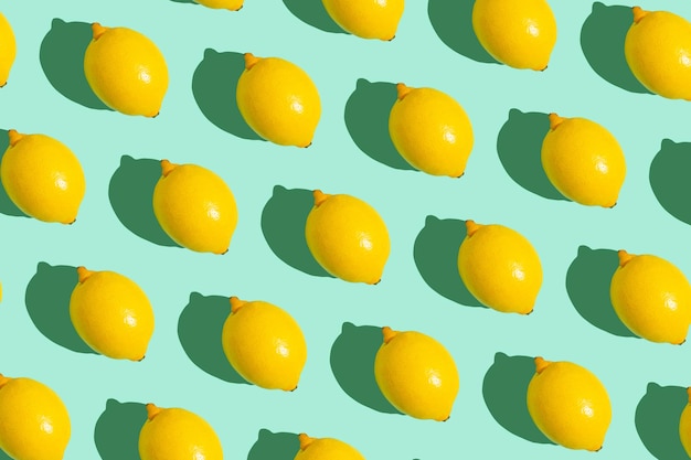 Yellow whole lemons on minimal blue background on bright sun light with hard shadows pattern