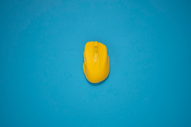 Yellow wireless computer mouse on a blue background Top view flat lay