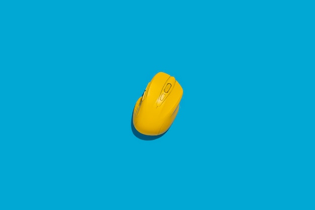 Yellow wireless computer mouse on a blue background Top view flat lay