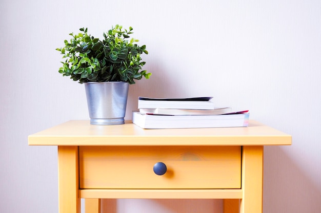 Foto tavolo in legno giallo con libro e vaso decorativo.