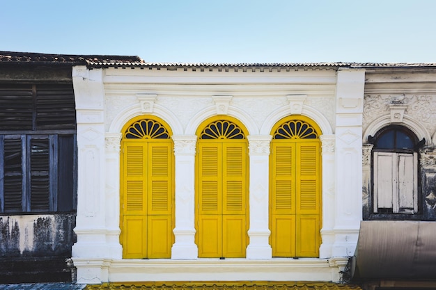 Photo yellow wooden arched window on a white cement wall in chino portuguese style at phuket thailand