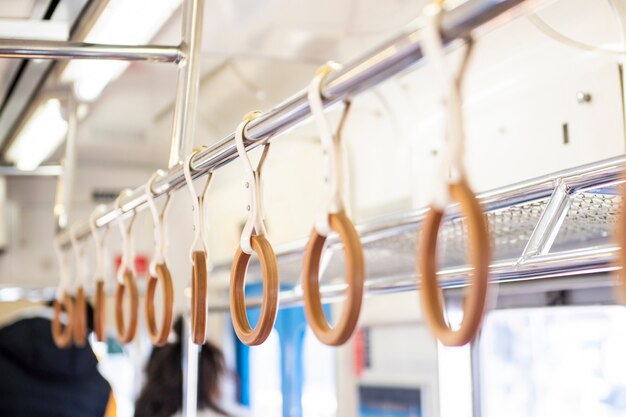 Yellow wooden  hand grip straps inside subway train