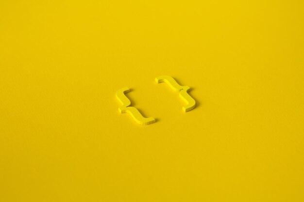 Yellow wooden symbol bracket on yellow background and copy space