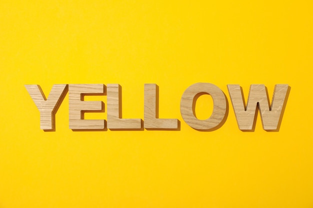 Yellow word made from wooden letters on yellow background