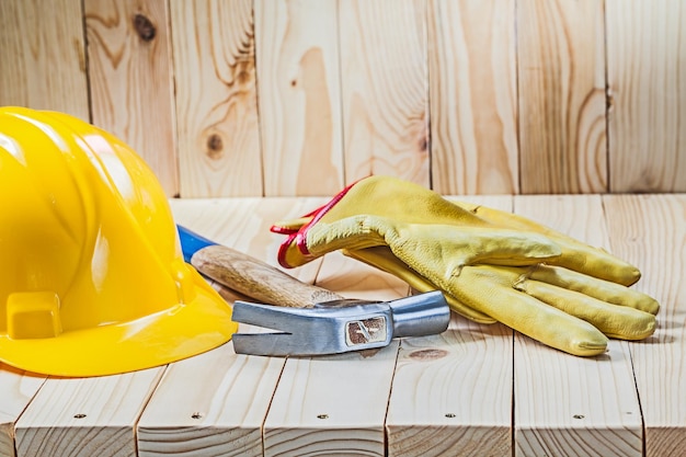 Yellow working gloves claw hammer and helmet on wooden background