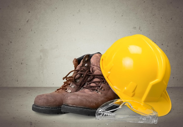 Yellow working hard hat and work boots on wooden background