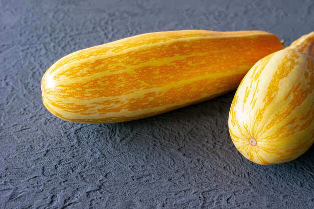 Yellow zucchini on grey background in colors of the year 2021 - Illuminating yellow and ultimate grey.