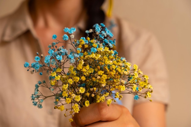 Yellowblue gypsophila bloemen in de hand van een vrouw Oekraïense symbolen