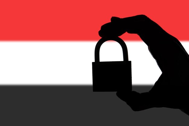 Yemen security Silhouette of hand holding a padlock over national flag