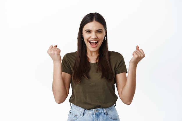 Yes I am winner Excited and delighted young woman fist pump scream from joy and excitement winning prize triumphing from achievement white background