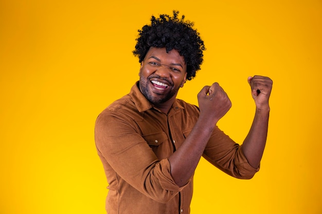 Yes i did afro man celebrating great luck and success looking\
at camera posing in studio over yellow background victory\
celebration joy emotion concept yes