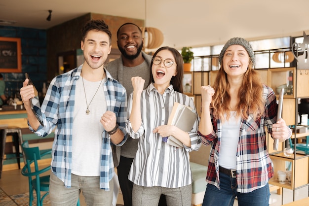 Foto sì, abbiamo fatto. felice gruppo di studenti internazionali è in piedi e mostra emotivamente eccitazione.