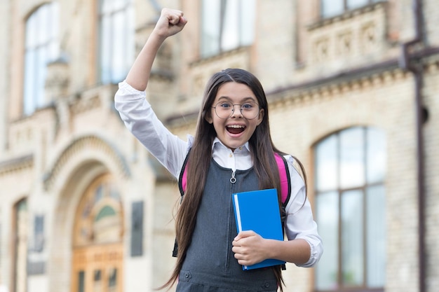 Sì, facciamo vincitori felice vincitore all'aperto il bambino piccolo fa un gesto vincente vincitore della borsa di studio successo nello studio ritorno a scuola educazione formale giornata della conoscenza 1 settembre puoi farcela