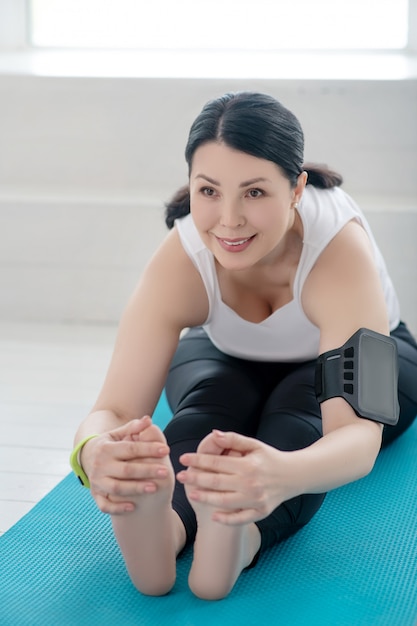 Yoga beoefening. Brunette vrouw zittend op tapijt, strekken, naar voren leunen