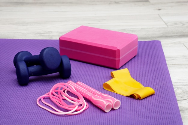 Yoga brick and jump rope on purple gym mat