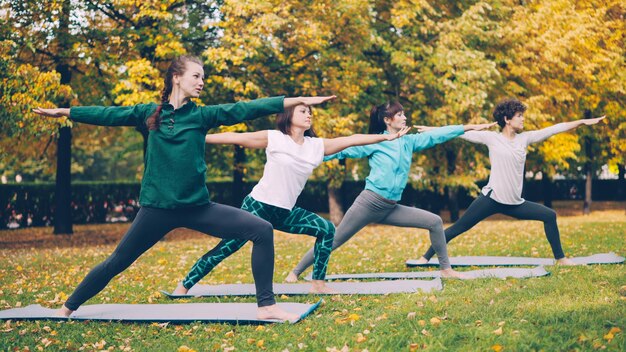 Фото Класс йоги делает упражнения на растяжку в парке, наслаждаясь осенней природой, свежим воздухом и физической активностью.