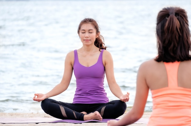 Photo yoga class at sea beach ,master guru doing lotus pose with clam