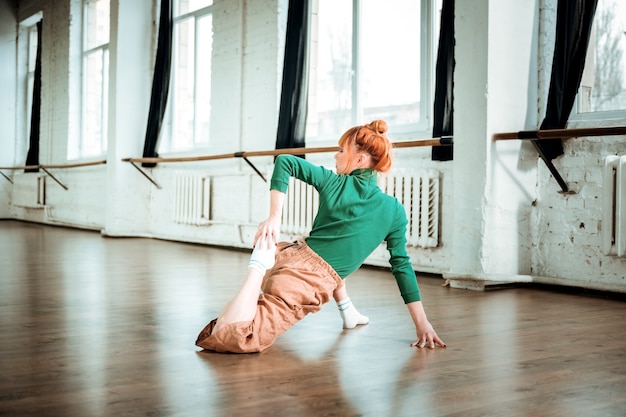 Yoga coach. professionele yogacoach die een groene coltrui draagt die yoga in een gymnastiek doet