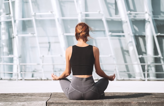 Yoga en meditatie in de stad Achteraanzicht van vrouw die mediteert en ademoefent buiten