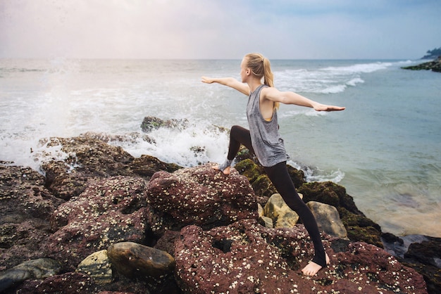 Esercizio di yoga sulla scogliera sul mare al tramonto