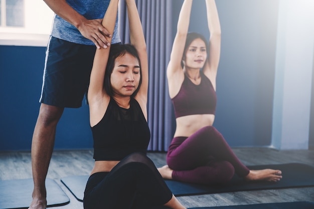 Yoga group concept; young man teaching woman practicing yoga in class; feeling Calmness and relax in yoga class