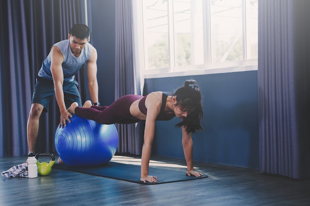 Yoga group concept; young man teaching woman practicing yoga in class; feeling Calmness and relax in yoga class