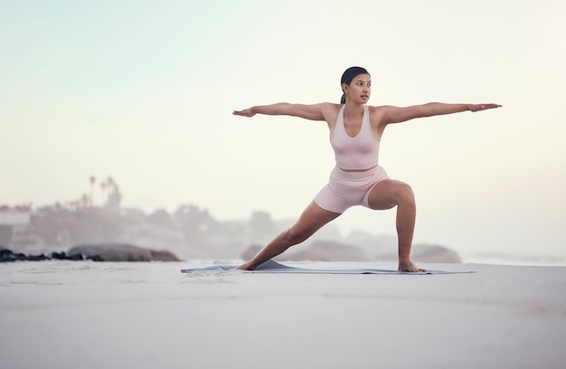 Yoga krijger pose en vrouw op het strand doen een meditatie voor zen in de natuur Zeezand en jongere met mindfulness training buiten om chakra-energie te kalmeren en te ontspannen met pilates aan de oceaan