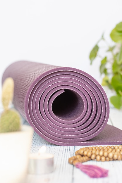 Foto stuoia di yoga, brutti branelli di legno su legno bianco. accessori essenziali per praticare yoga e meditazione.