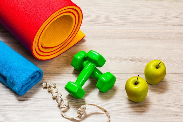 Yoga mat and different tools for fitness on floor in room