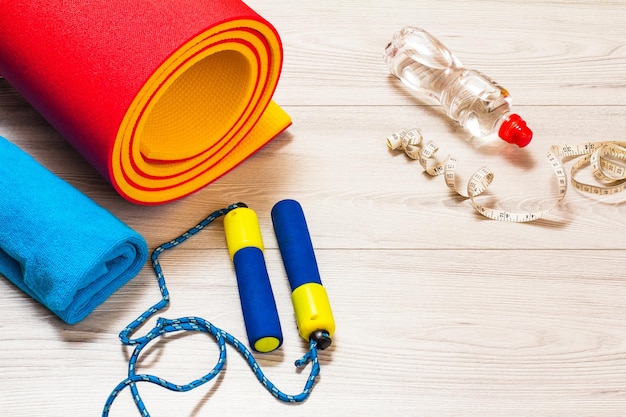 Yoga mat and different tools for fitness on floor in room